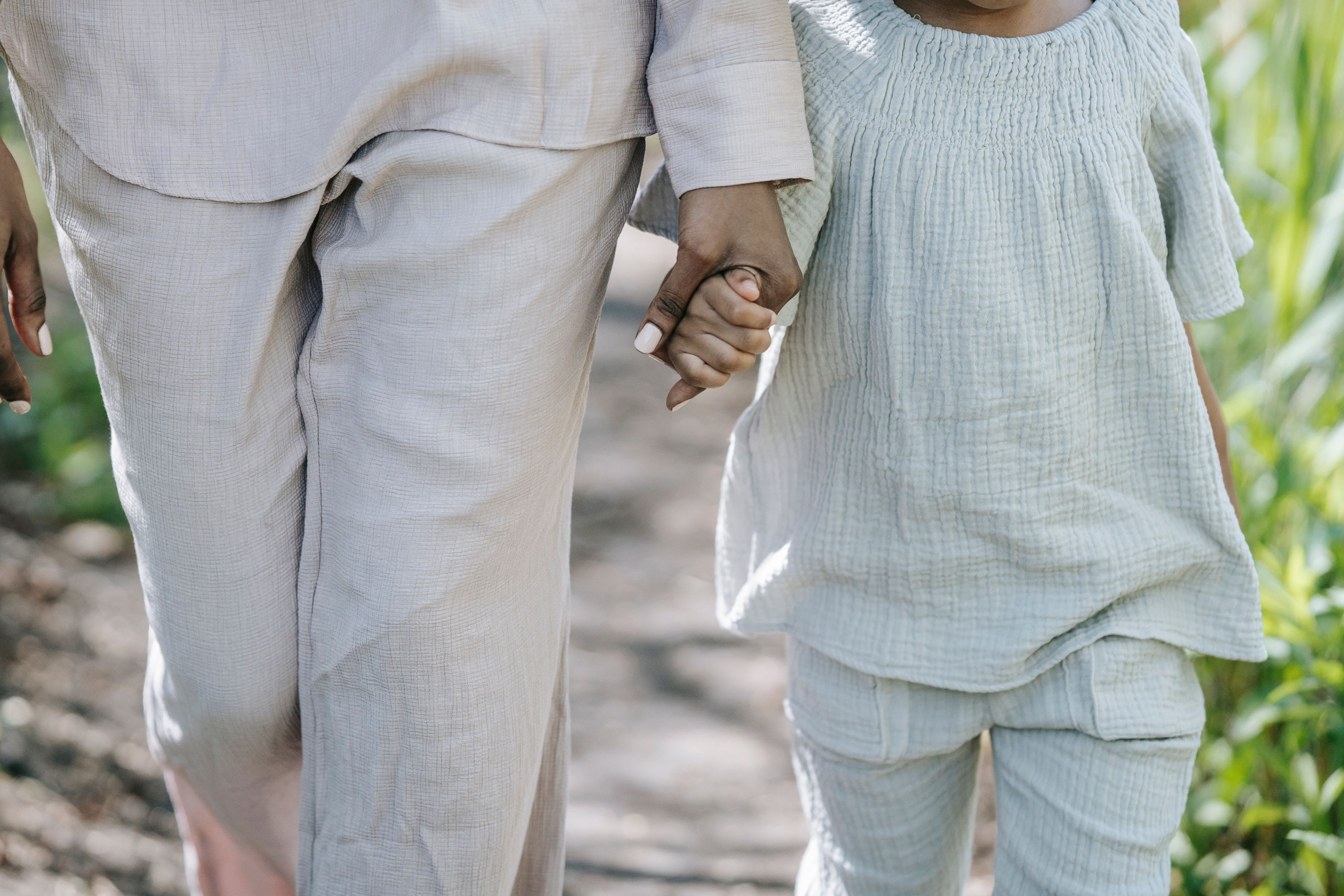 A parent and child hand in hand, hands clasped