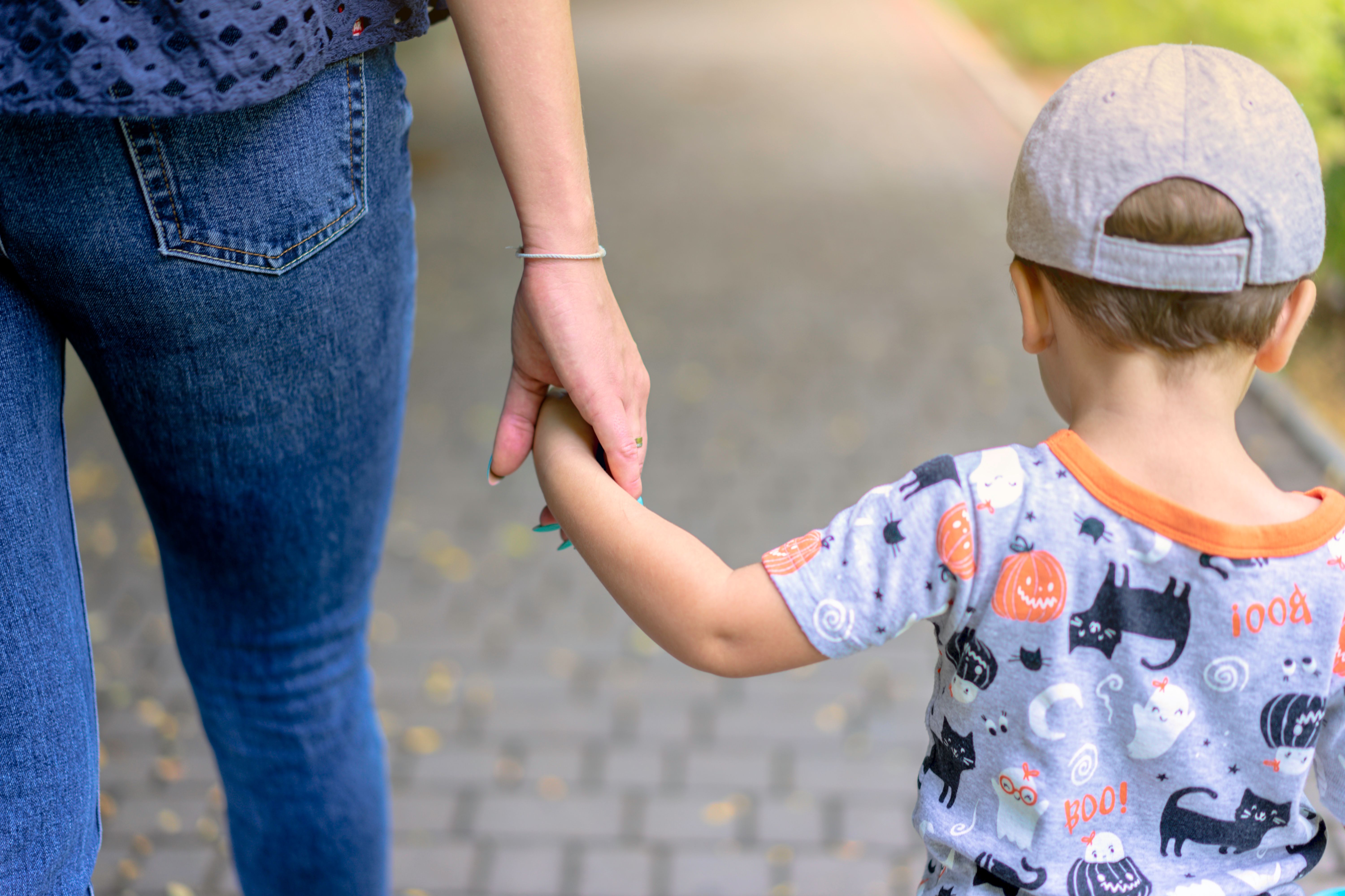 A caregiver takes a child's hand on the walk home